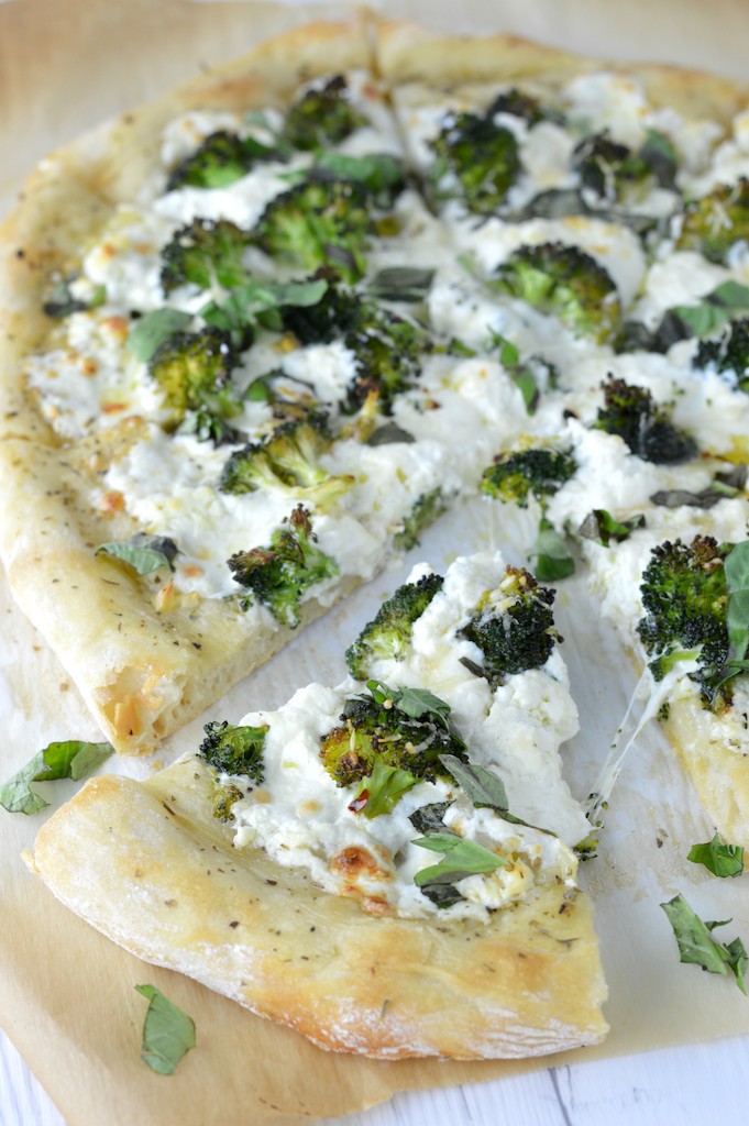 slice of four cheese white broccoli pizza pulled from rest of pizza