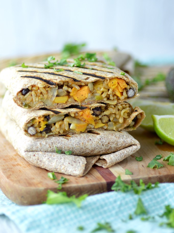 sweet potato black bean burritos stacked on each other on cutting board