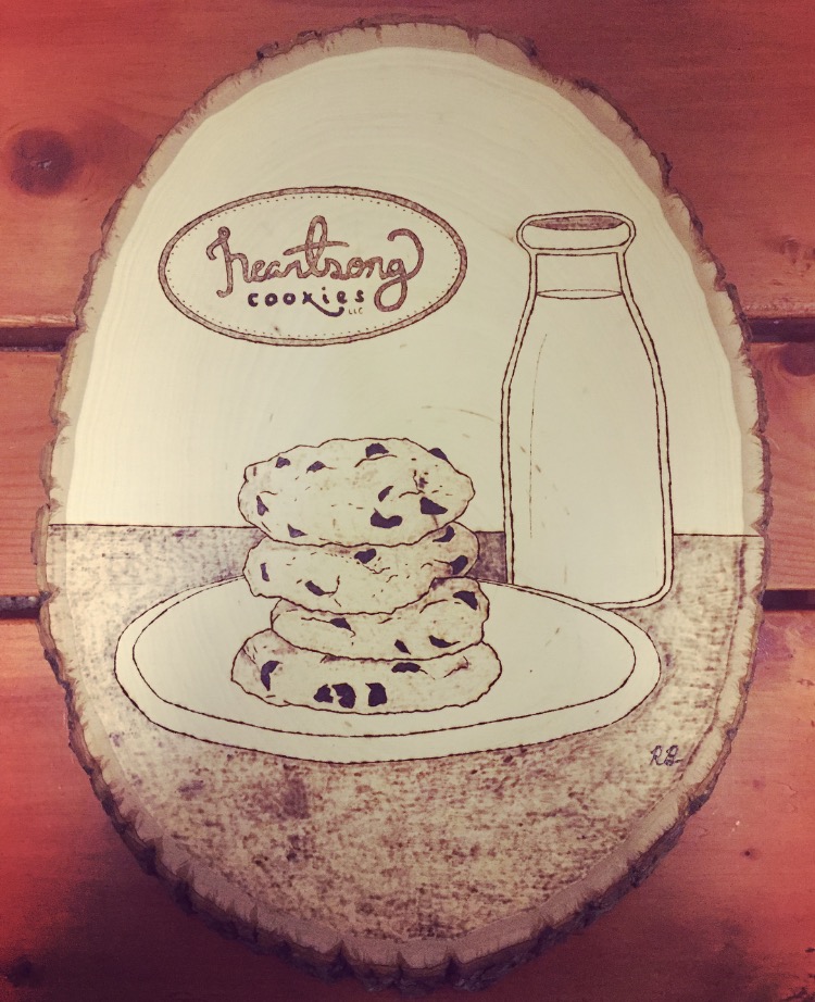 overhead shot of piece of wood with cookies and milk woodburned into it