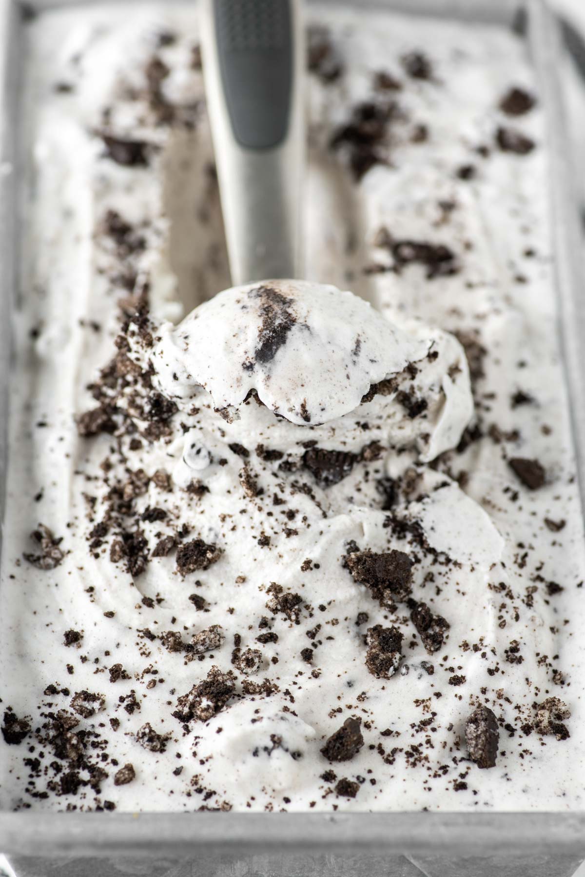 cookies and cream ice cream being scooped out of metal tin