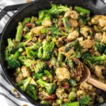 one pan pesto chicken and veggies in cast iron skillet with wooden spoon dipped in