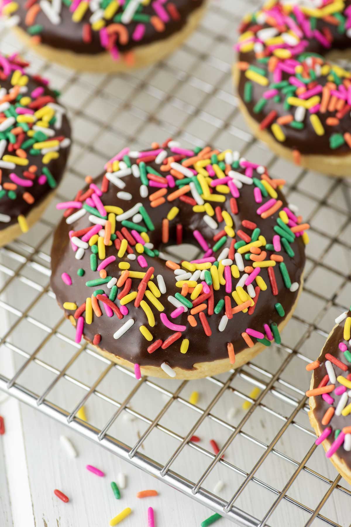 chocolate frosted donut with sprinkles on cooling rack