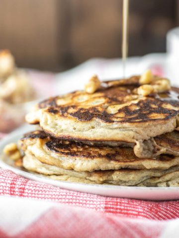 maple syrup drizzled on stacked apple ricotta pancakes