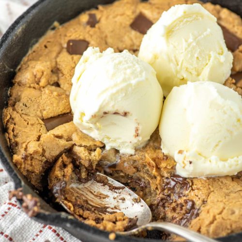 spoon dipped in chocolate chip peanut butter skillet cookie with ice cream