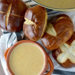 overlay of beer cheese soup recipe in orange bowl with pretzels