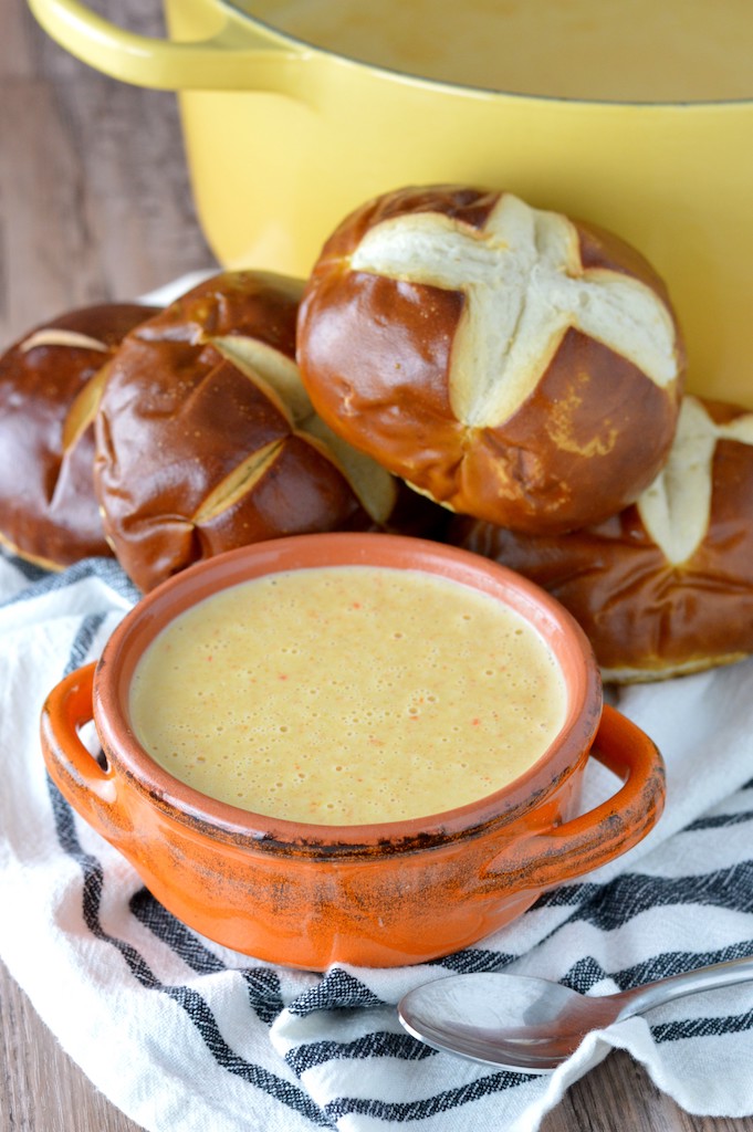 close-up of beer cheese soup recipe in orange bowl with pretzels
