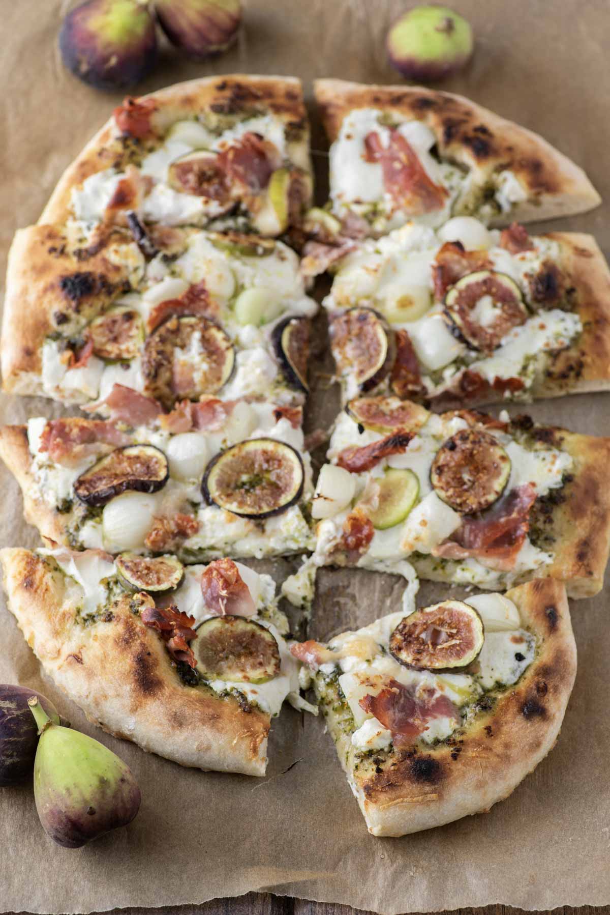 sliced up fig prosciutto pizza on parchment paper