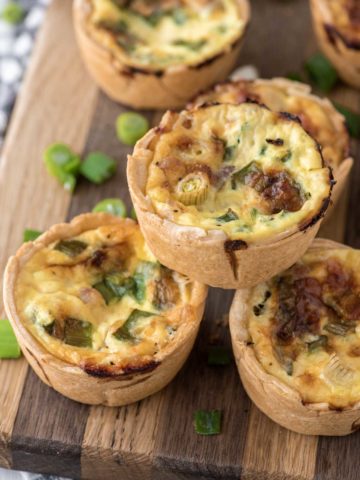 mini ham and cheese quiche stacked on cutting board