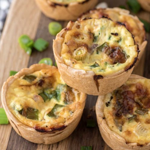 mini ham and cheese quiche stacked on cutting board