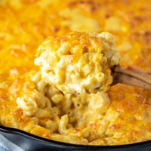 spoonful of baked cheddar mac and cheese pulled from skillet