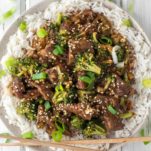 overhead shot of beef and broccoli with chopsticks on plate