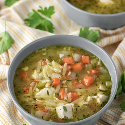lemon chicken orzo soup in bowl on dish towel