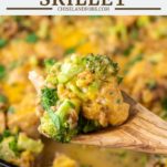wooden spoon lifting out chicken, farro, broccoli and cheese from skillet