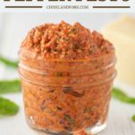 red pepper pesto in glass jar with spoonful on floor