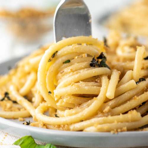fork twirling garlic butter pasta on gray plate
