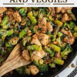 wooden spoon dipped in pesto chicken and veggies in cast iron skillet