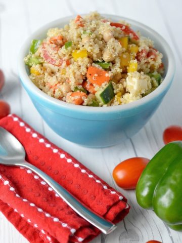 Summer quinoa salad in blue bowl with tomatoes and green pepper