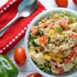 Overhead of summer quinoa salad in blue bowl with tomatoes and green pepper