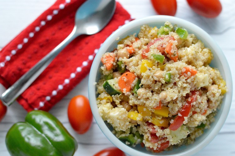 Overhead of summer quinoa salad in blue bowl with tomatoes and green pepper