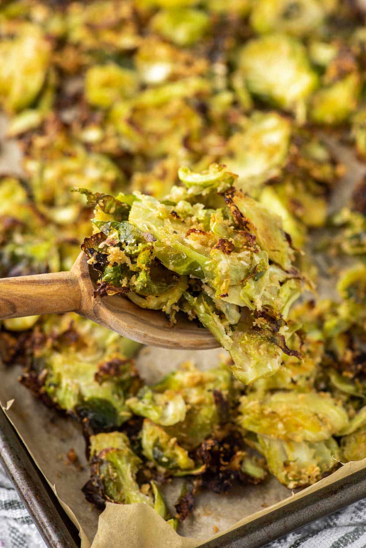wooden spoon lifting out parmesan roasted Brussel sprouts