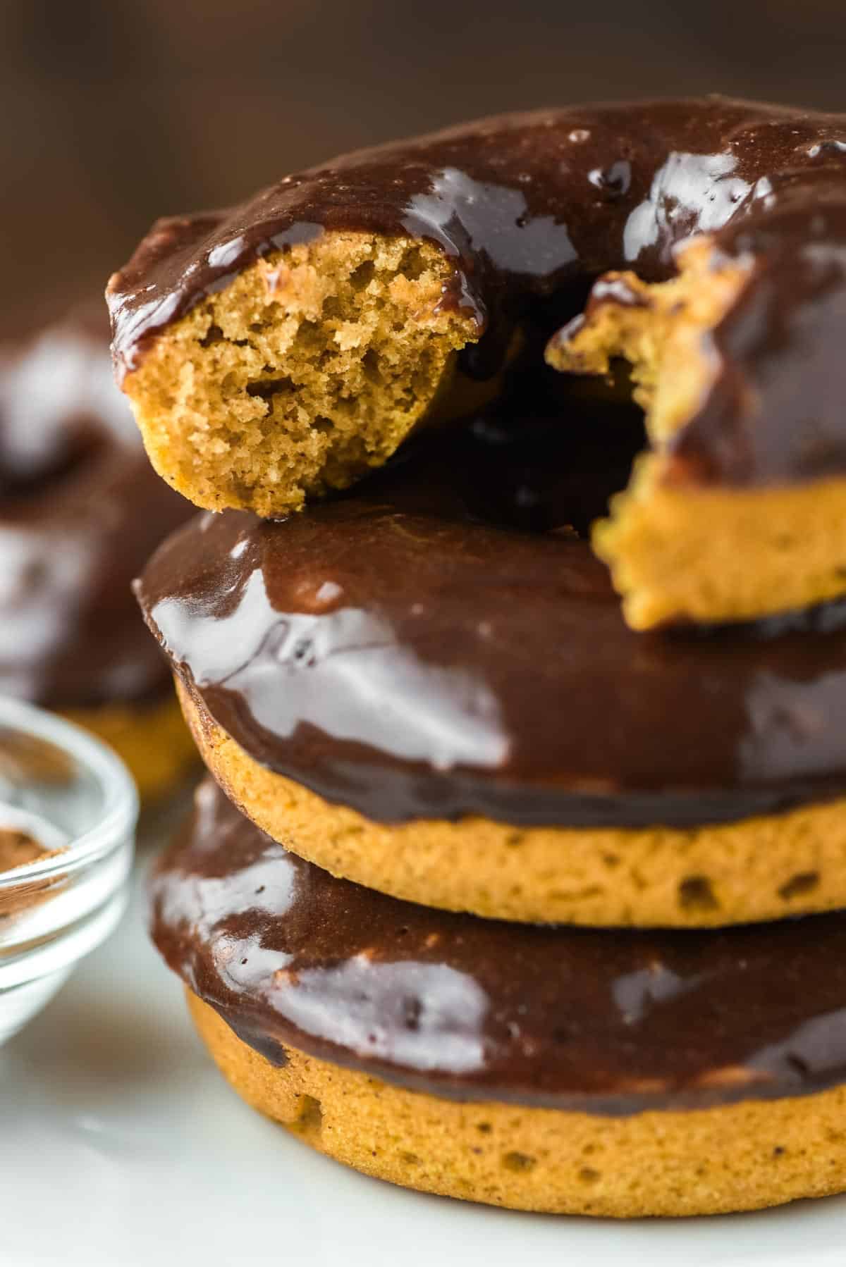 bite taken out of baked pumpkin donut on top of two other donuts