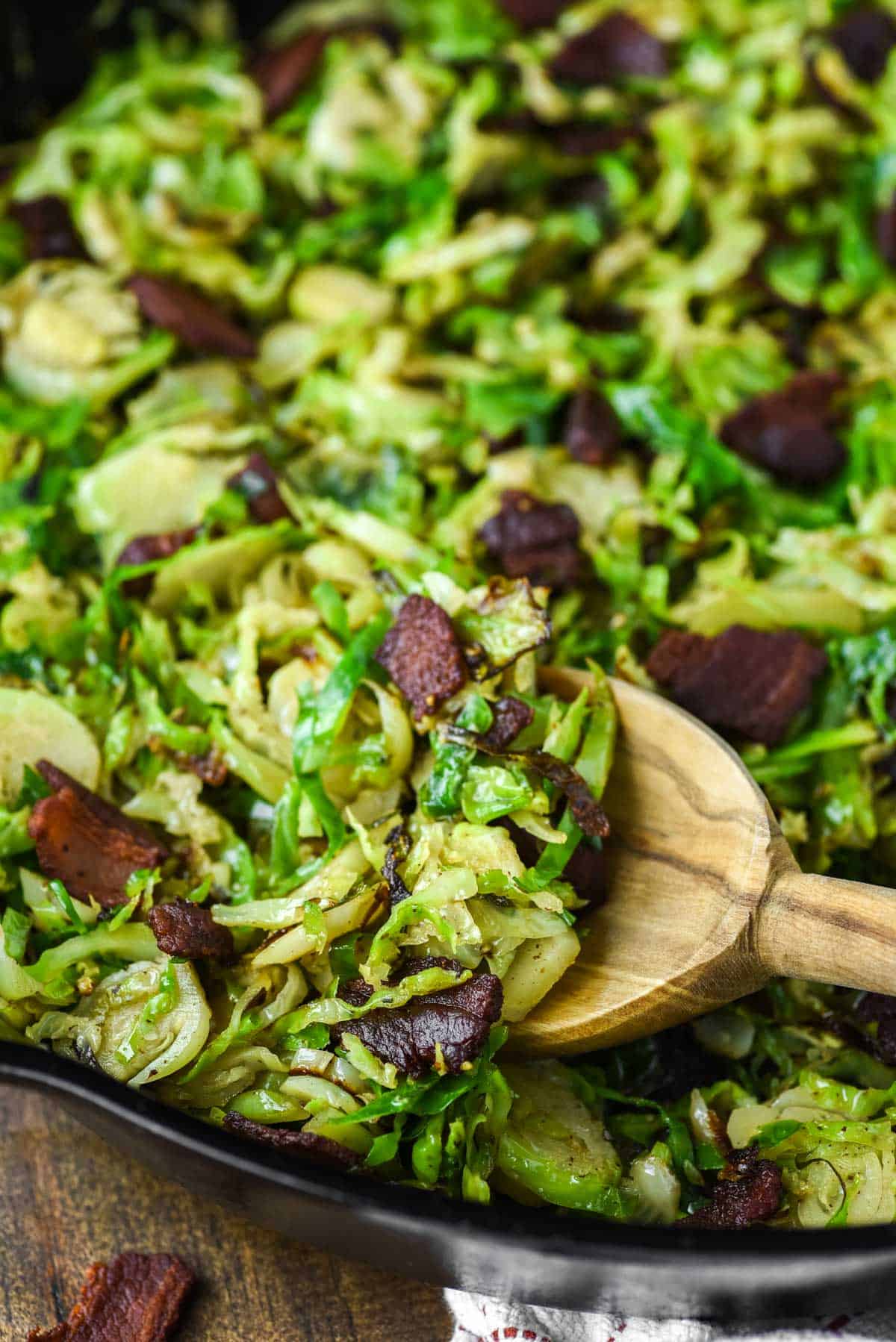 wooden spoon dipped in skillet with brussels sprouts