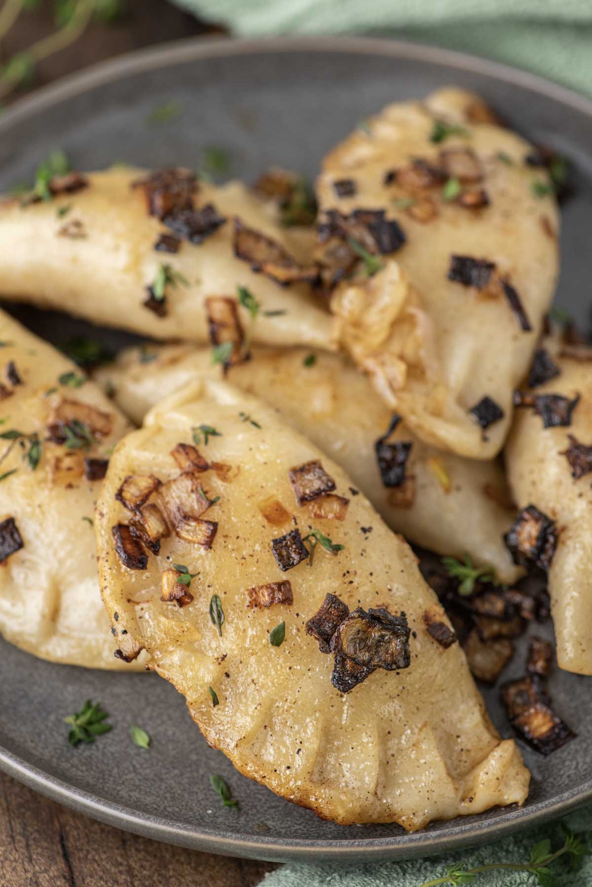 homemade cheddar pierogies on plate with sauteed onions