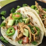 two Instant pot chicken tacos on black plate