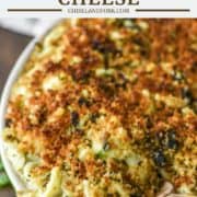 wooden spoon dipped in green baking dish of pesto mac and cheese