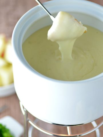 close-up of classic cheese fondue with bread dipping in cheese