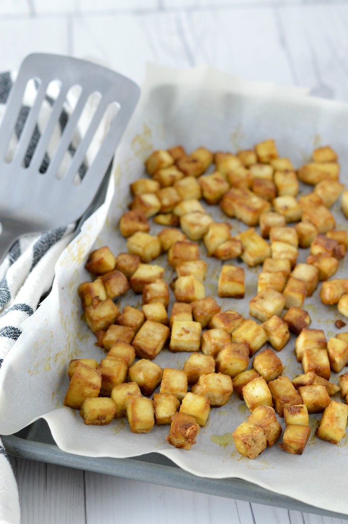 close-up of crispy baked tofu in baking sheet with spatula