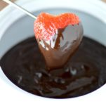close-up of strawberry dipped in dark chocolate fondue