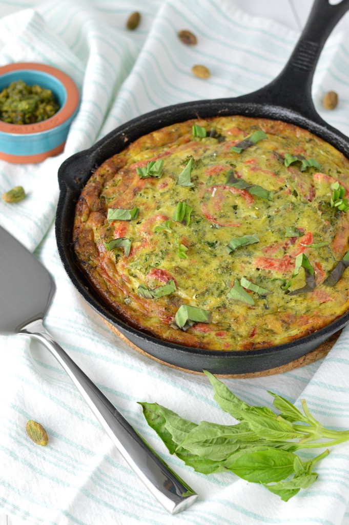 Italian frittata in cast iron skillet with fresh basil and pistachios