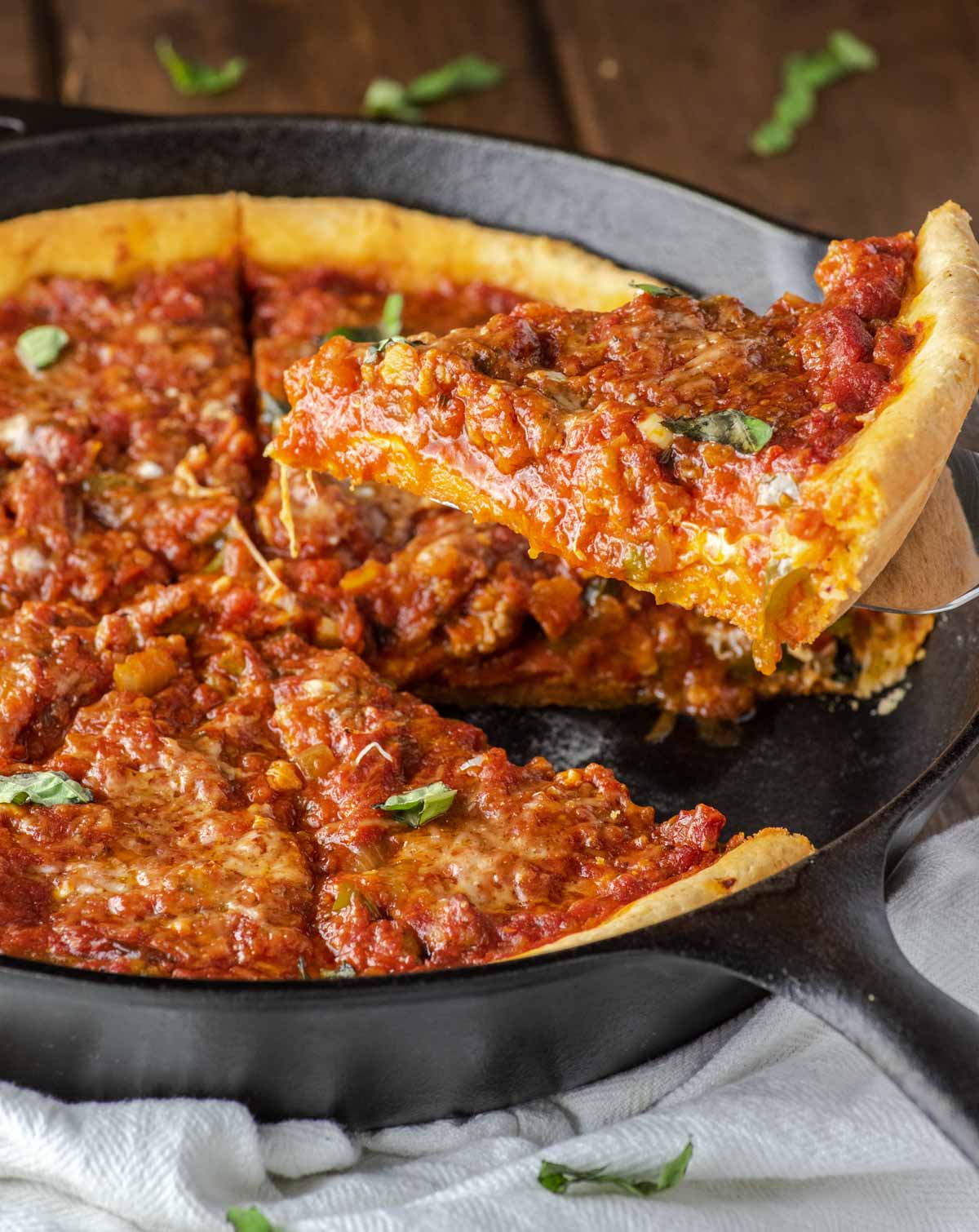 close-up of chicago-style deep dish pizza slice being pulled from skillet