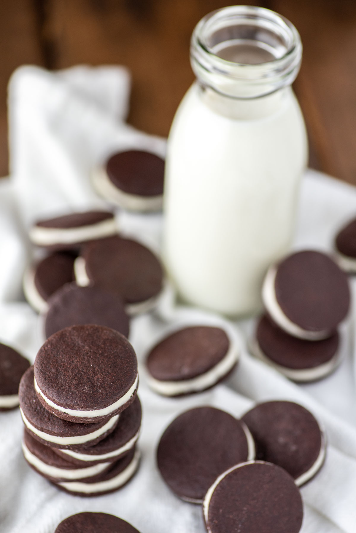 close-up of stacked homemade oreos on white kitchen towel with glass of milk