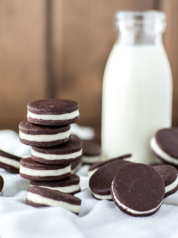 close-up of stacked oreo cookies on white kitchen towel with glass of milk