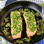close-up of salmon with chimichurri in skillet