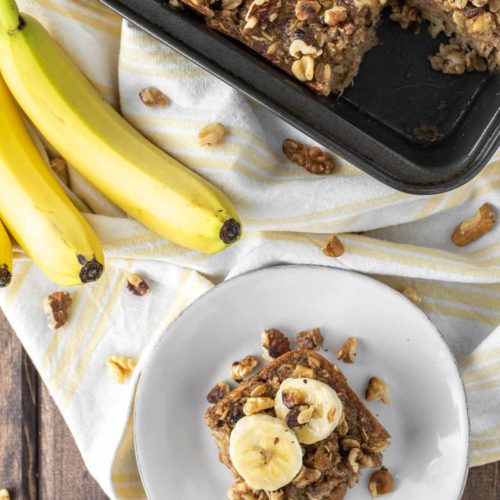 overhead shot of banana baked oatmeal on white plate and in square baking pan