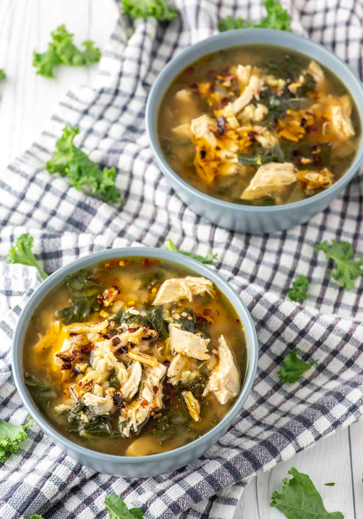 chicken barley soup in two blue bowls on dish towel