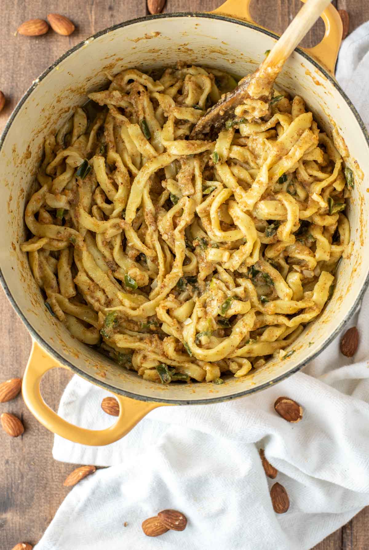 overhead shot of almond pesto fettuccine in yellow dutch oven with white dish towel