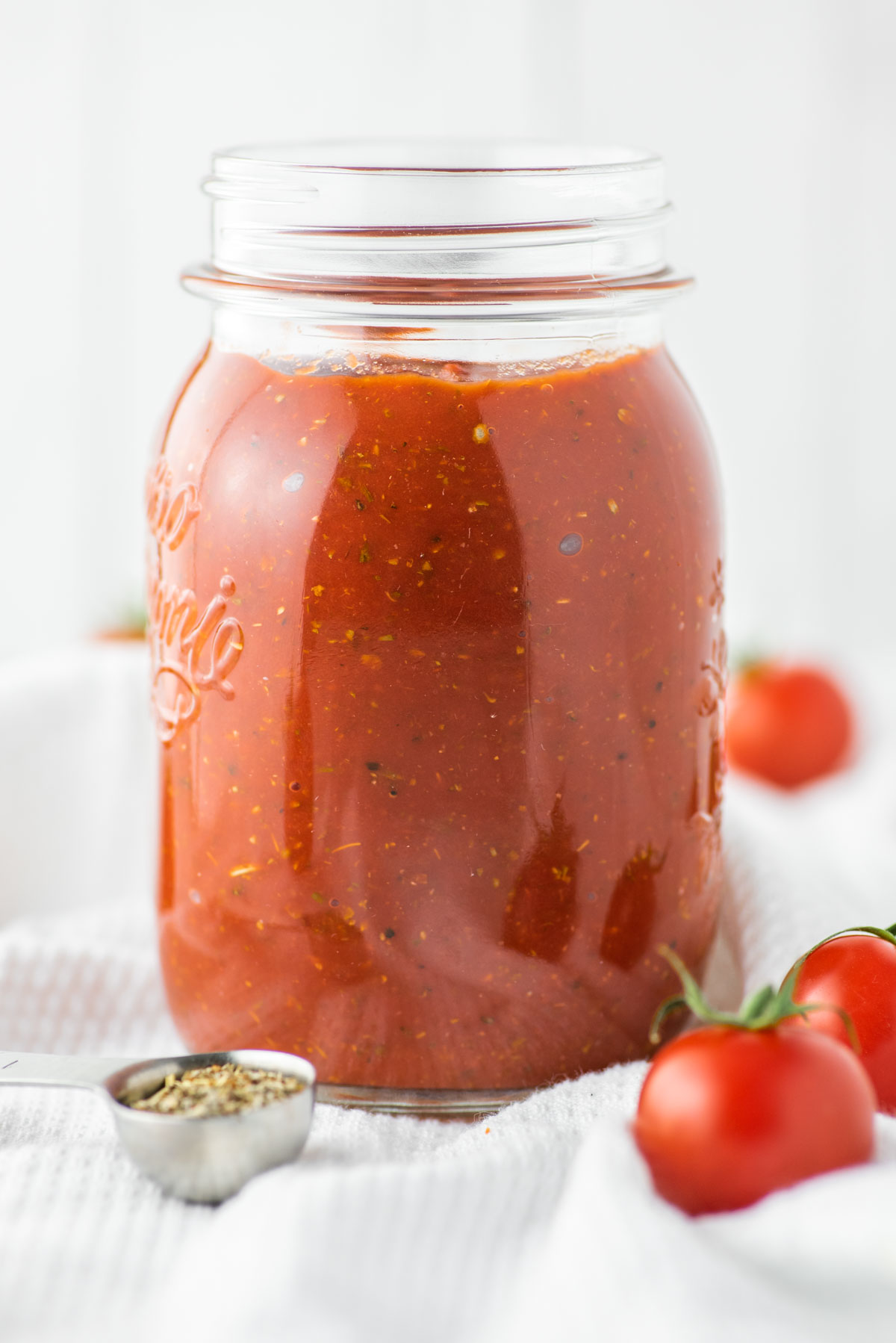 homemade pizza sauce in glass jar with fresh tomatoes