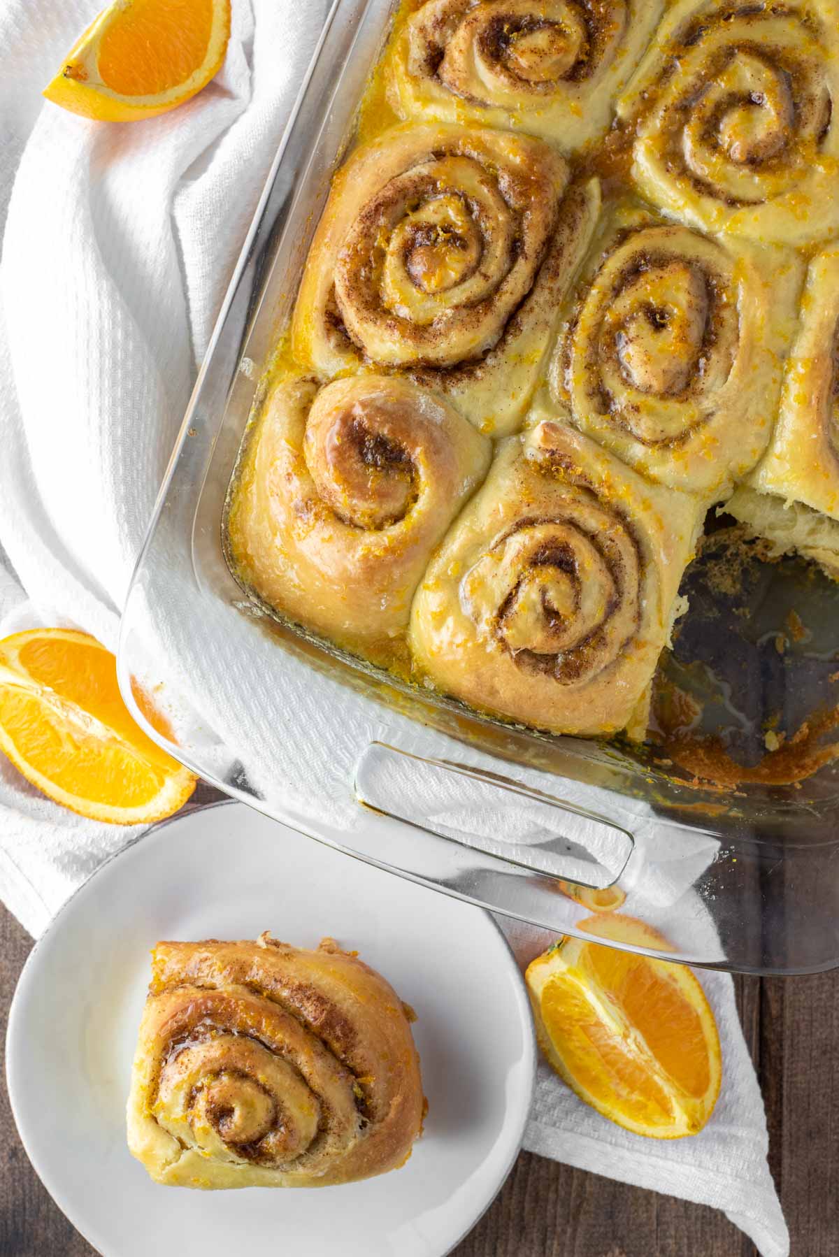 overhead shot of orange rolls in baking dish and on white plate
