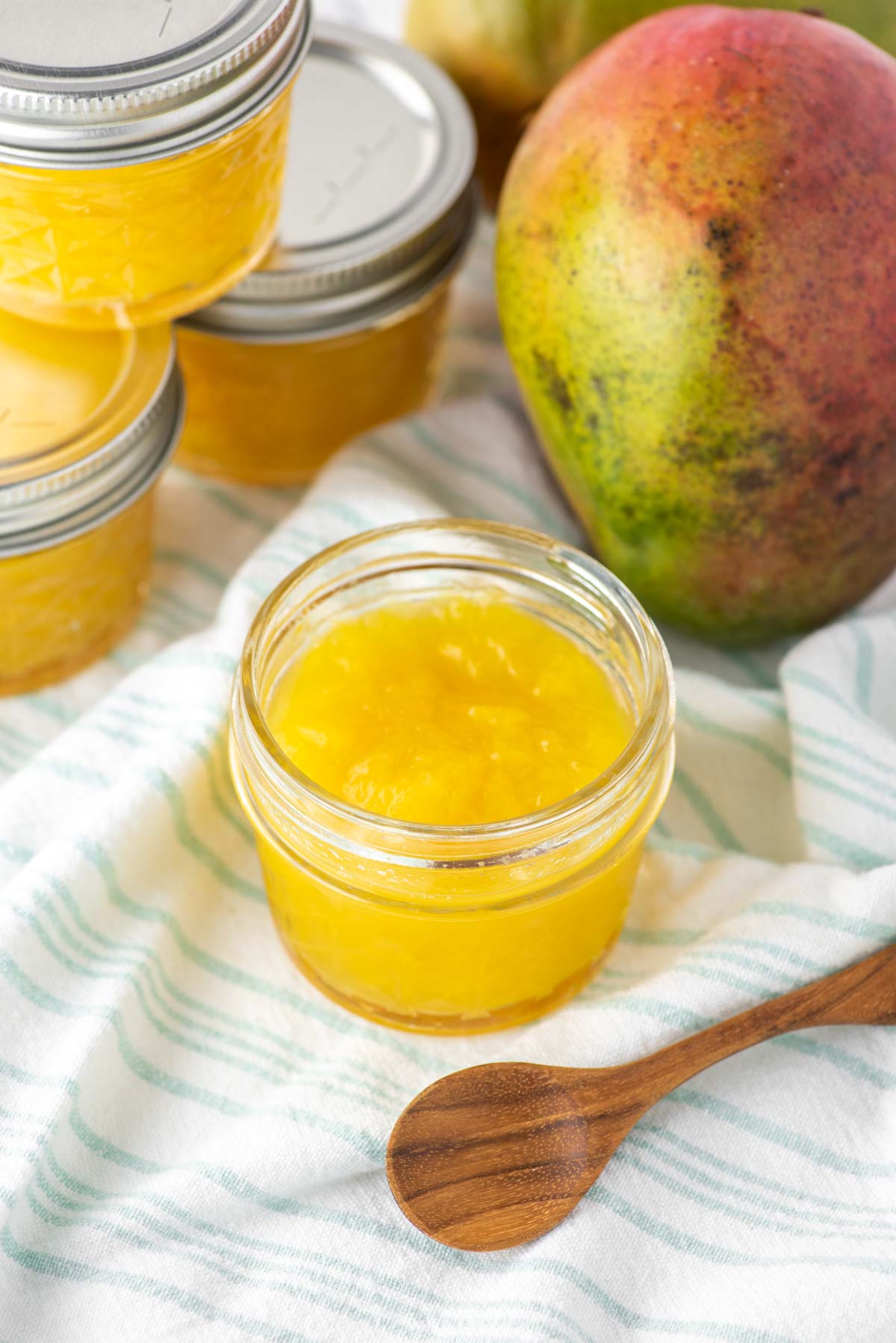 jam in glass jar with fresh mango in background
