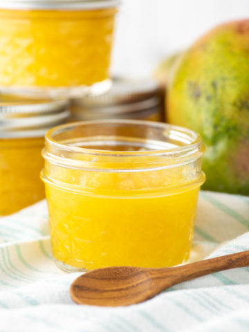 mango jam in glass jar with more jars in background
