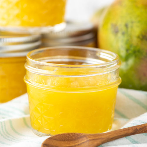 mango jam in glass jar with more jars in background