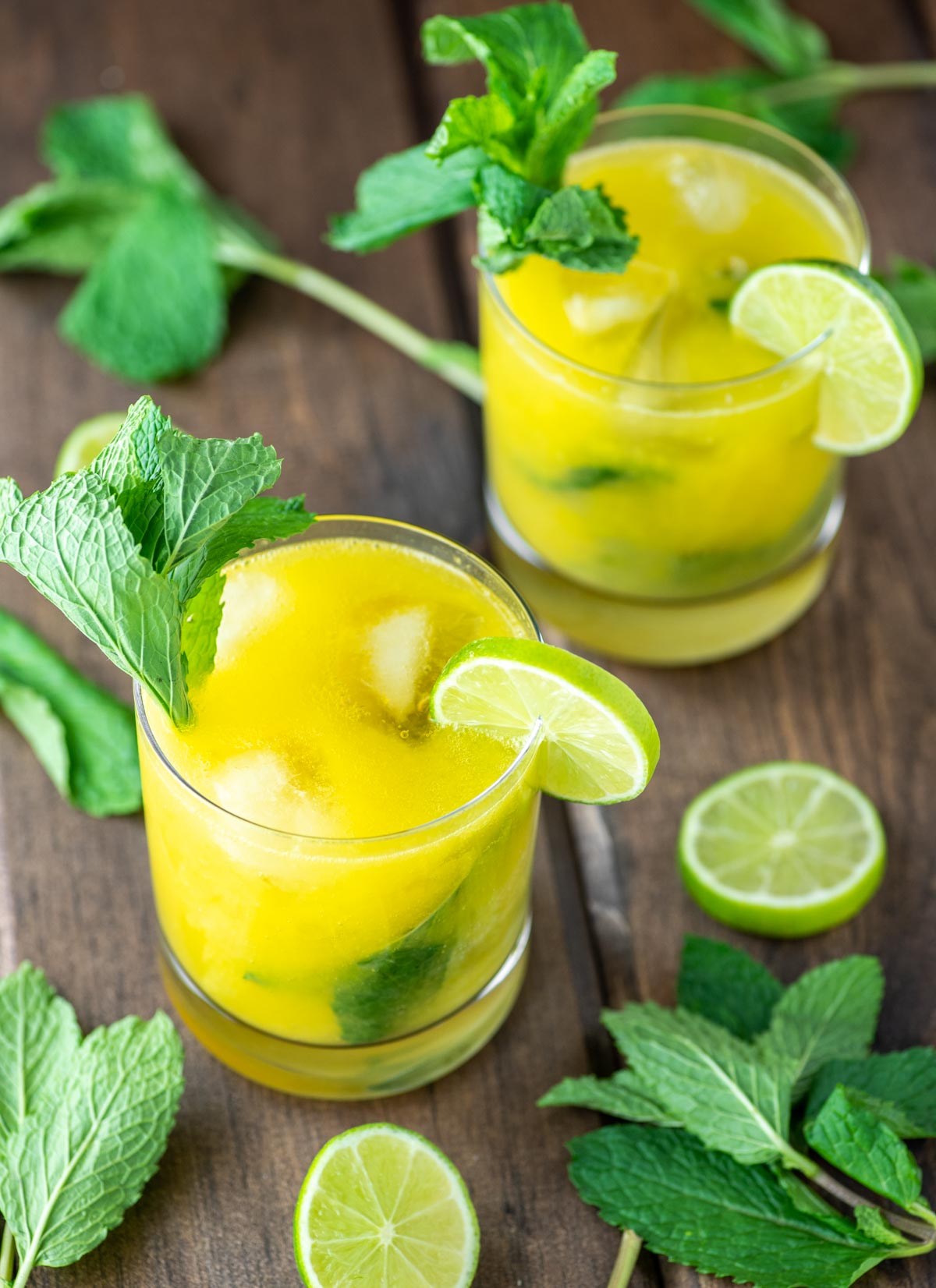 two mango mojitos in glasses with fresh minth