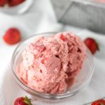 strawberry ice cream in glass bowl with container in background