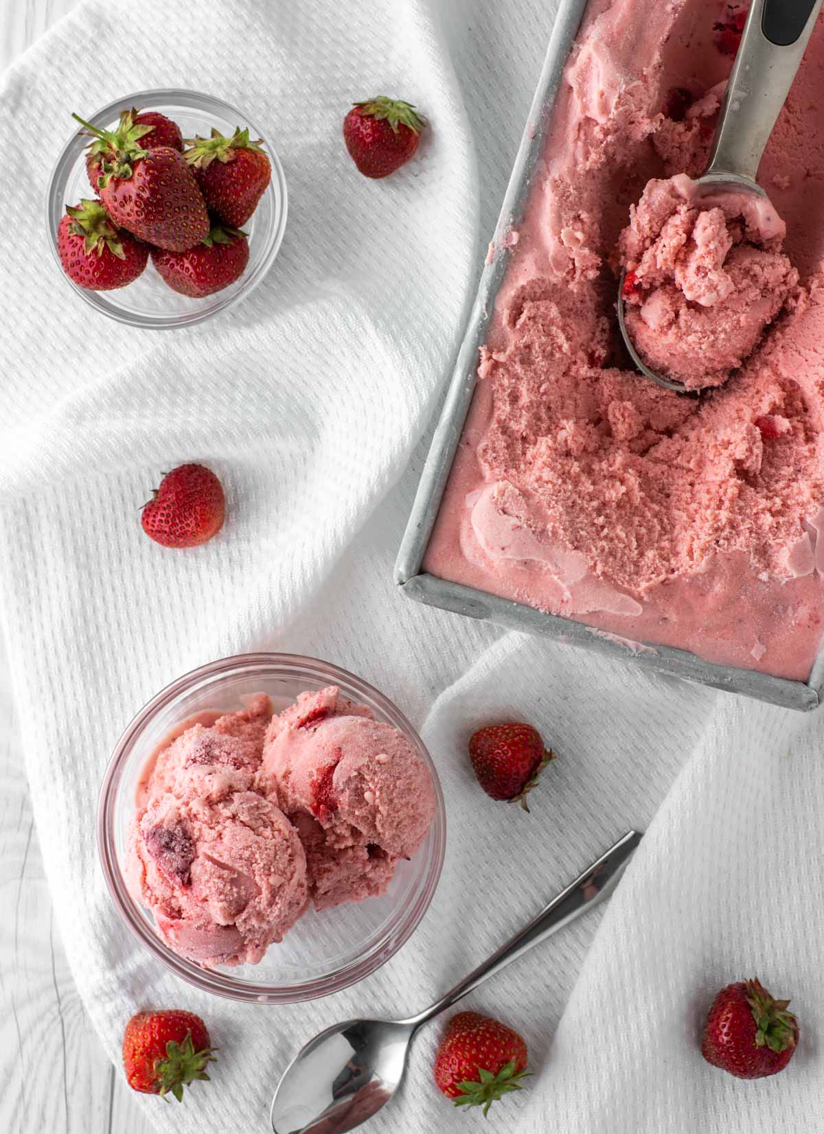 overhead shot of strawberry ice cream in glass bowl and container