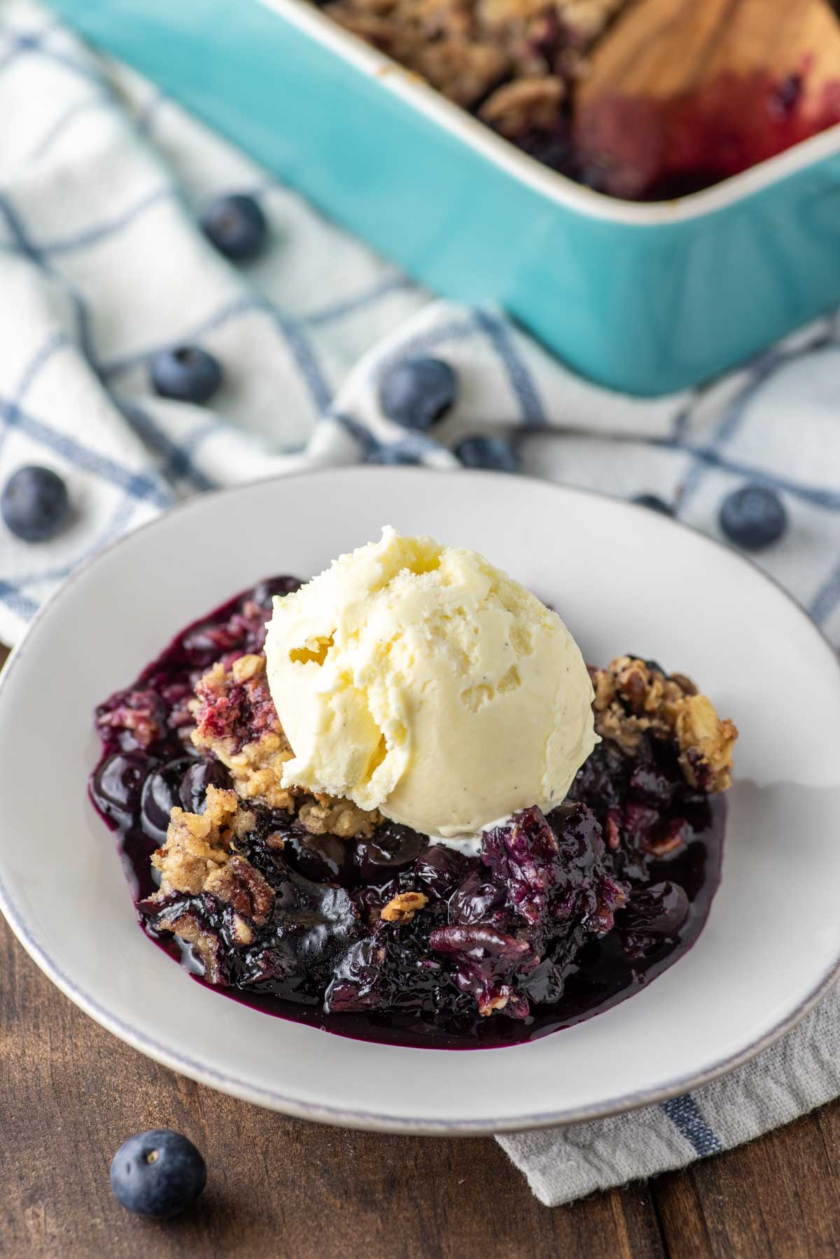 blueberry crisp on plate topped with ice cream