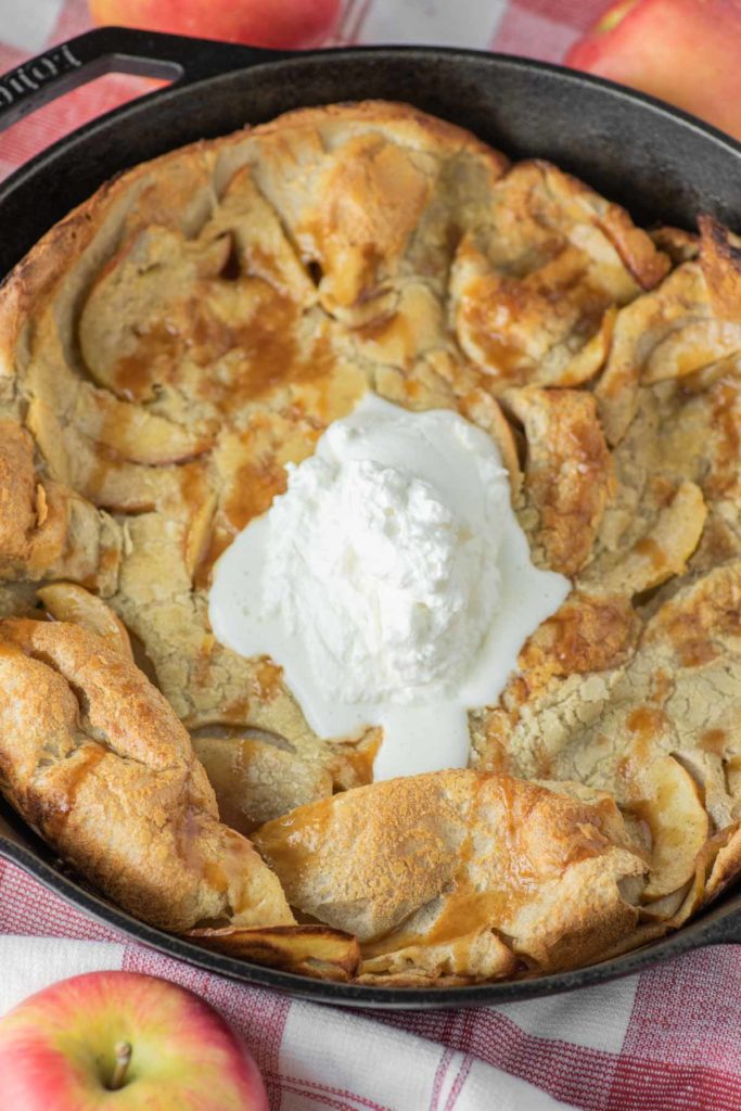 apple dutch baby with whipped cream in skillet